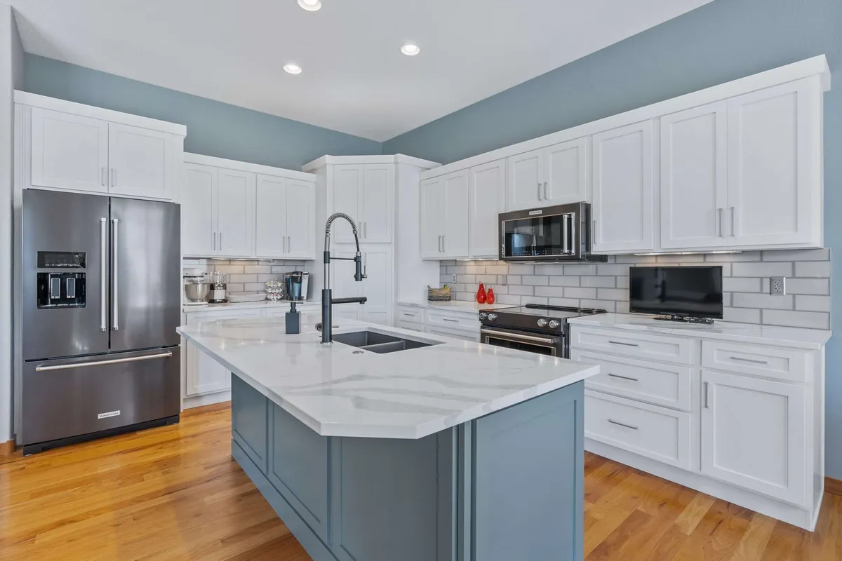 After — Knotty wood to bright white, blue-grey island